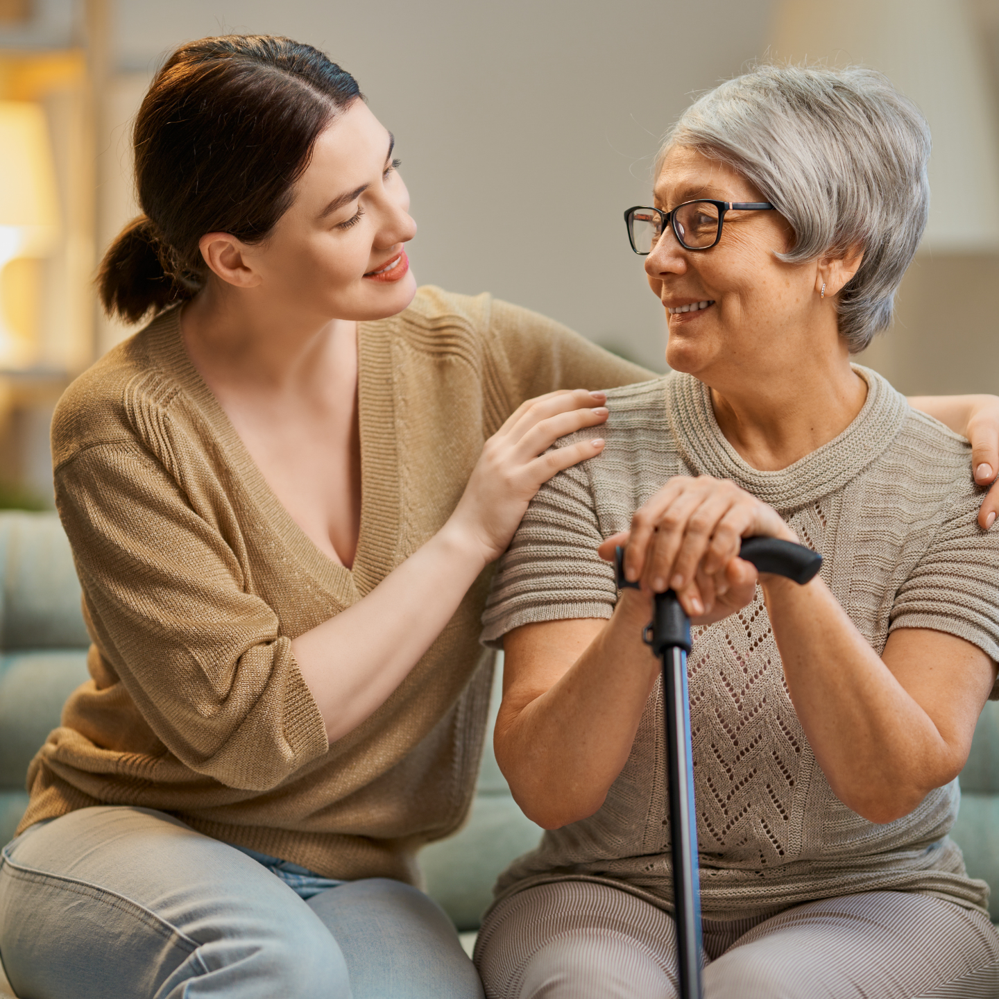 A woman touching an older woman with a cane